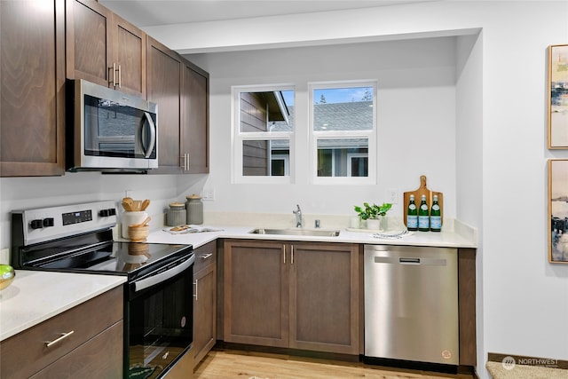 kitchen with sink, dark brown cabinets, stainless steel appliances, and light wood-type flooring