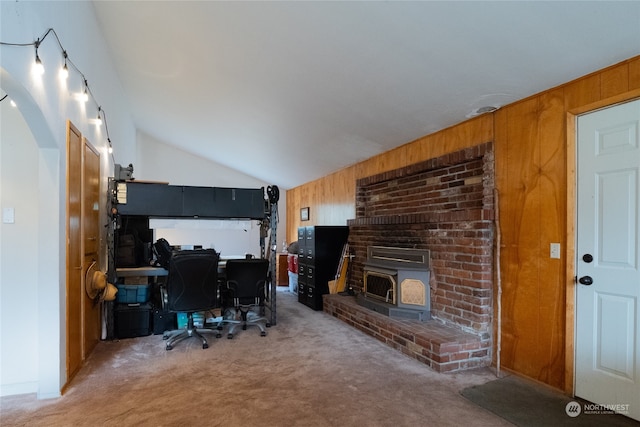 carpeted office featuring a wood stove, wood walls, and lofted ceiling