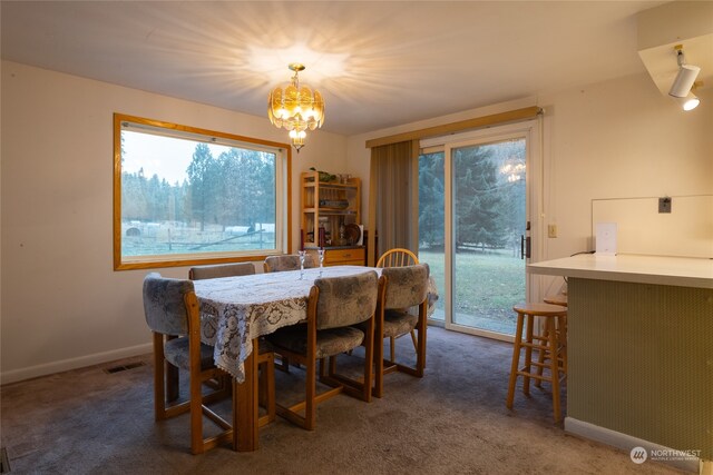 dining area with dark carpet and a notable chandelier