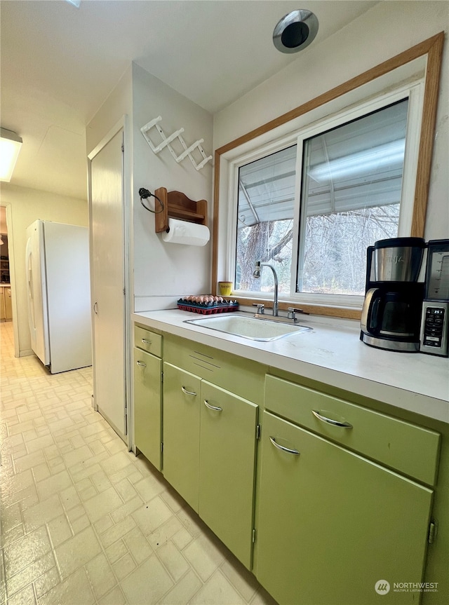 kitchen featuring white fridge, green cabinets, and sink