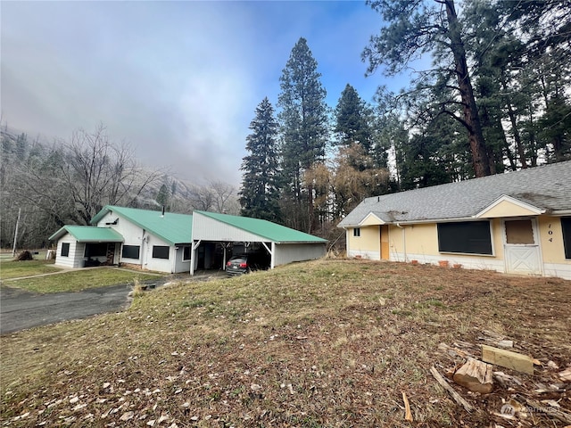 view of home's exterior with an attached carport, aphalt driveway, and roof with shingles
