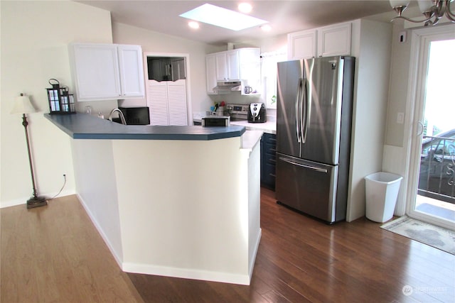 kitchen with appliances with stainless steel finishes, vaulted ceiling with skylight, dark wood-type flooring, kitchen peninsula, and white cabinets