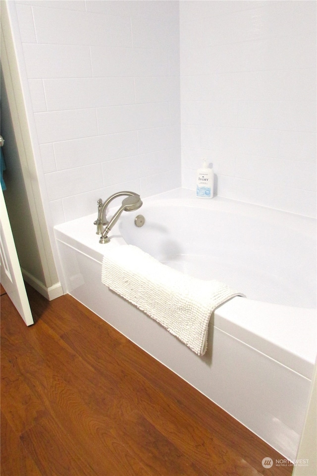 bathroom with hardwood / wood-style flooring and a washtub