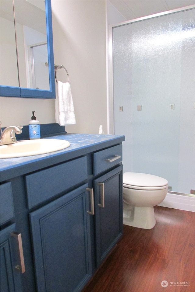 bathroom featuring toilet, vanity, an enclosed shower, and wood-type flooring