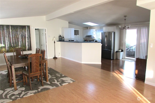 dining room featuring lofted ceiling with skylight, a chandelier, and dark hardwood / wood-style floors