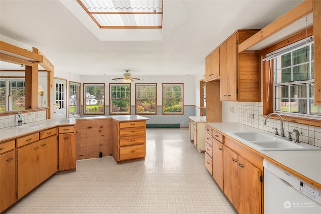 kitchen featuring a skylight, sink, white dishwasher, and a baseboard heating unit