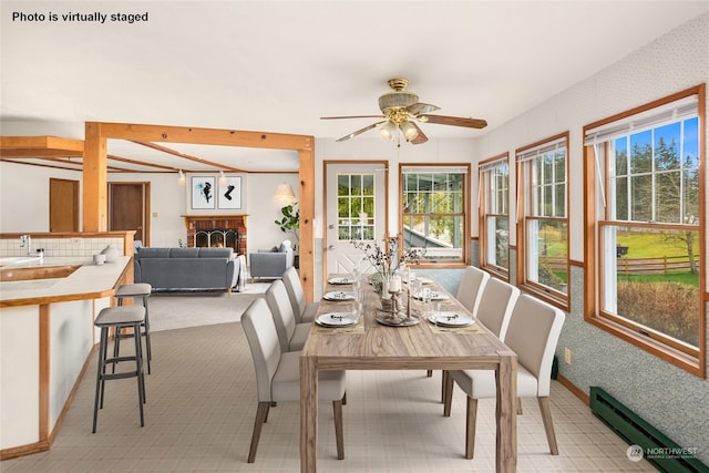 carpeted dining space with ceiling fan, a fireplace, and a baseboard heating unit