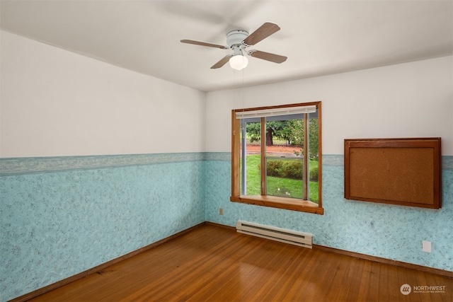 spare room featuring hardwood / wood-style flooring, ceiling fan, and a baseboard heating unit