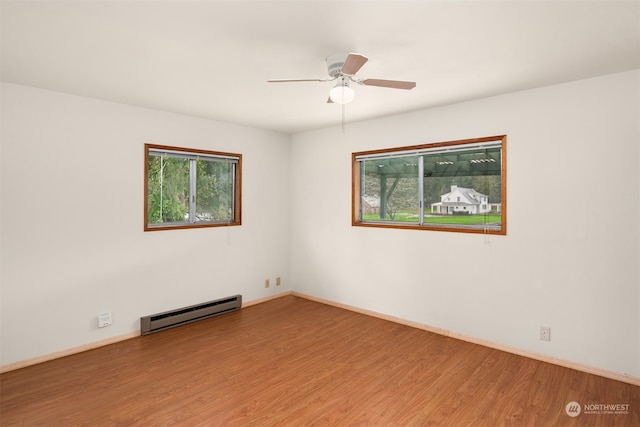 empty room with hardwood / wood-style floors, ceiling fan, and a baseboard heating unit