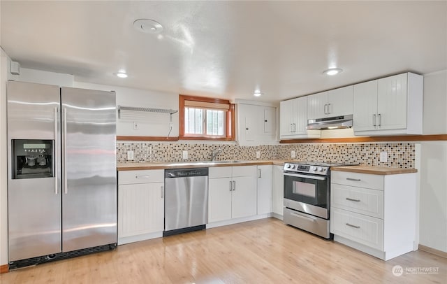 kitchen featuring stainless steel appliances, backsplash, butcher block countertops, light hardwood / wood-style floors, and white cabinets