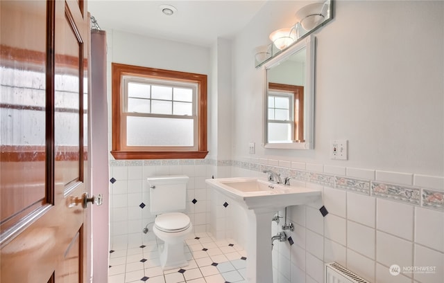 bathroom featuring tile patterned floors, sink, tile walls, and toilet