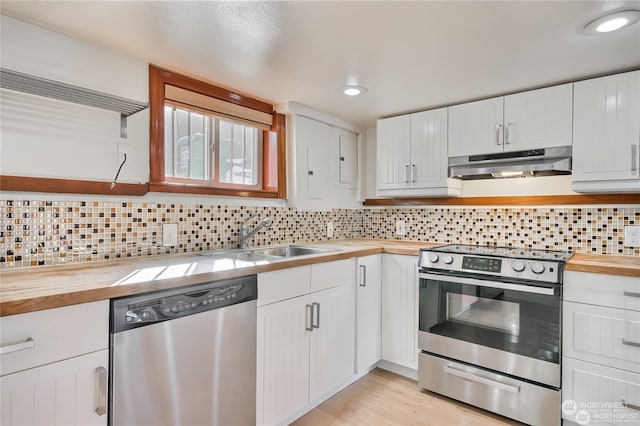 kitchen featuring white cabinets, decorative backsplash, butcher block counters, and appliances with stainless steel finishes