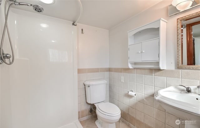 bathroom with sink, walk in shower, tile patterned flooring, toilet, and tile walls