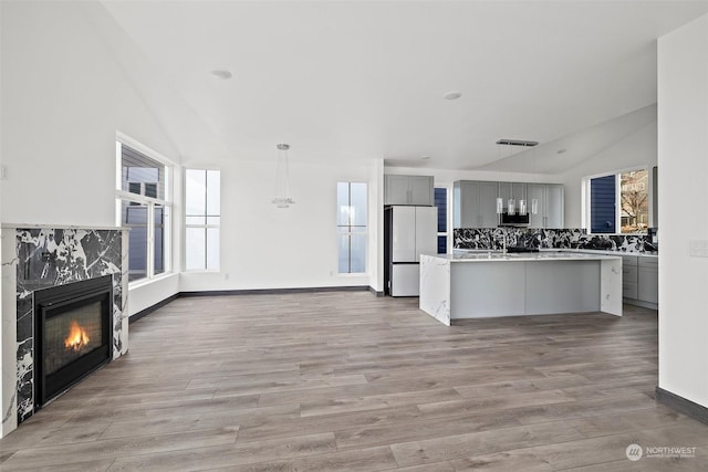 kitchen featuring gray cabinetry, a wealth of natural light, vaulted ceiling, and white refrigerator