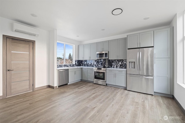 kitchen with light wood-type flooring, sink, appliances with stainless steel finishes, and a wall mounted AC