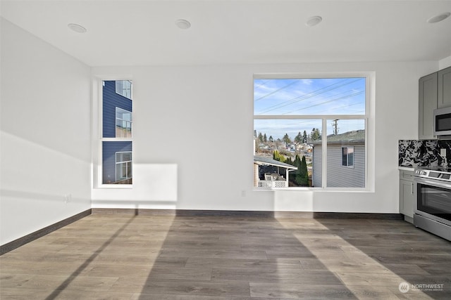 interior space featuring appliances with stainless steel finishes, tasteful backsplash, gray cabinetry, and wood-type flooring