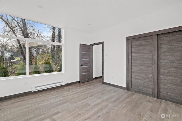 unfurnished bedroom featuring a closet, a baseboard radiator, and light hardwood / wood-style floors