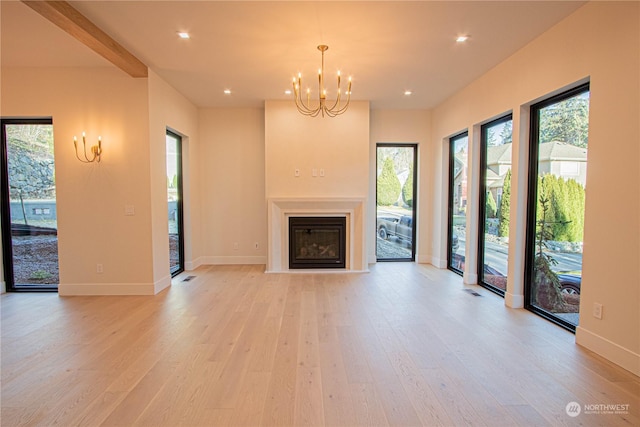 unfurnished living room with a chandelier and light wood-type flooring