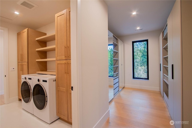 laundry room featuring cabinets, washer and dryer, and light hardwood / wood-style flooring