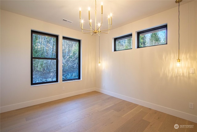 spare room with wood-type flooring and a chandelier