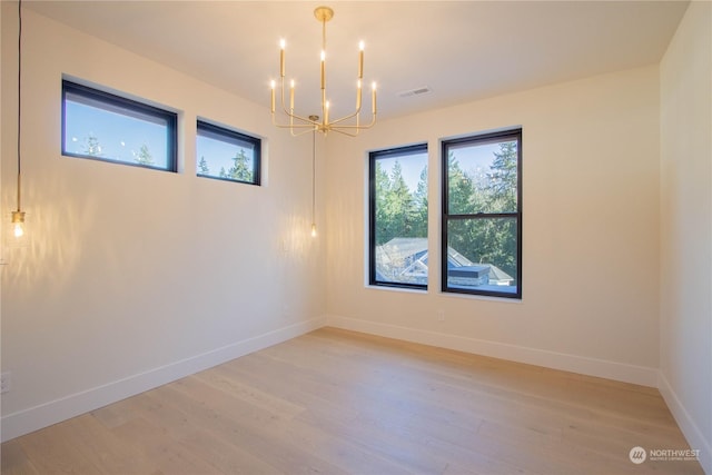 spare room featuring a notable chandelier and light hardwood / wood-style flooring