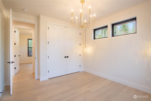 unfurnished bedroom with light hardwood / wood-style floors, a closet, and a chandelier