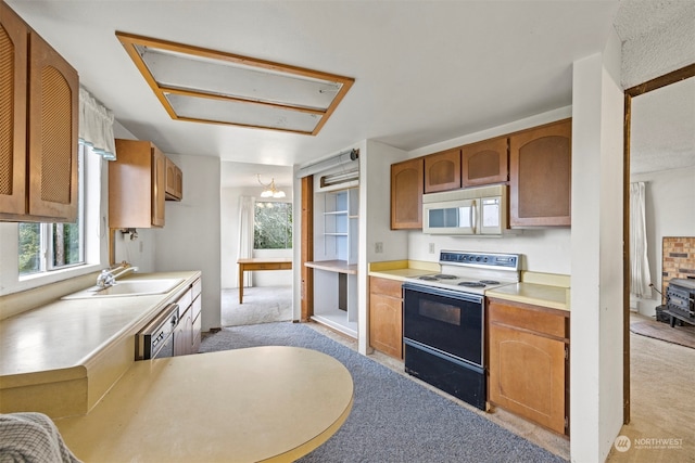 kitchen with white appliances, light carpet, a wood stove, sink, and kitchen peninsula