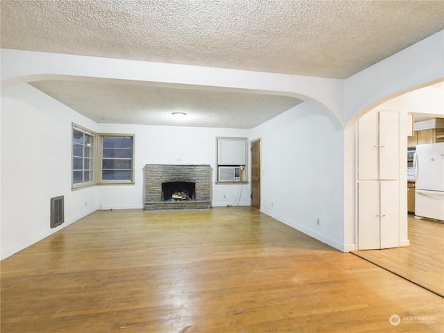 unfurnished living room featuring a fireplace, hardwood / wood-style floors, and a textured ceiling