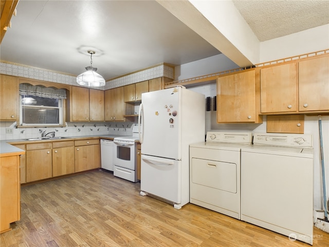 kitchen with white appliances, sink, hanging light fixtures, washer and dryer, and light wood-type flooring