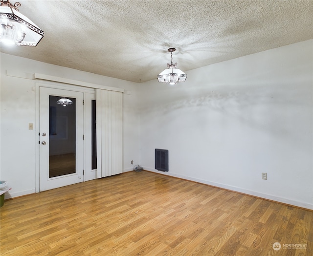 unfurnished room with light hardwood / wood-style flooring and a textured ceiling