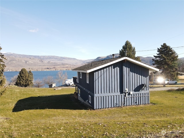 view of side of home with a storage unit, a yard, and a water and mountain view