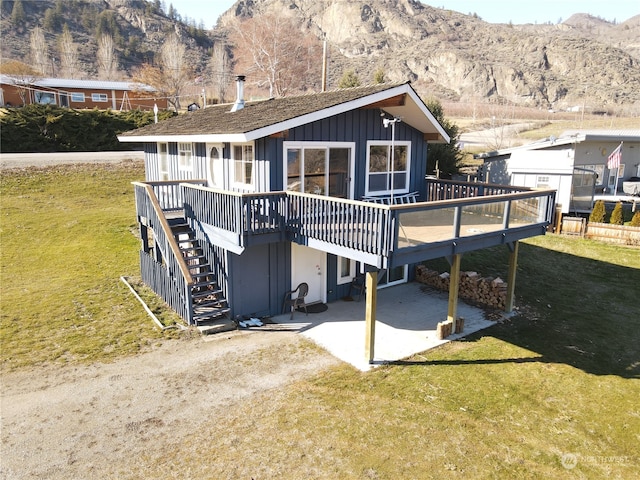 back of house with a lawn, a patio area, and a deck with mountain view