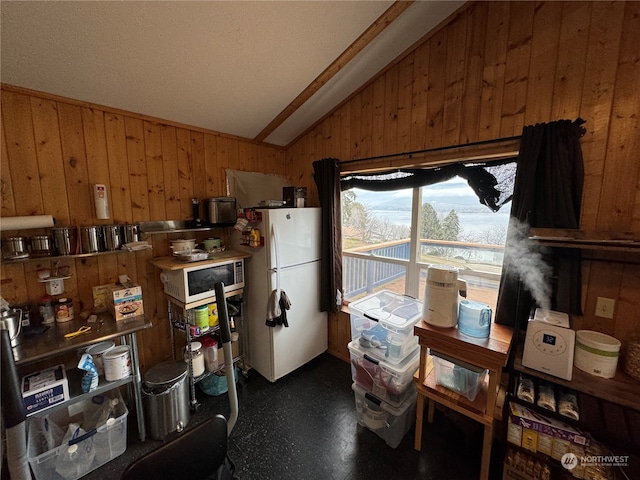 kitchen featuring white refrigerator, vaulted ceiling, and wood walls