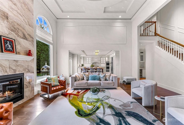 living room with a high end fireplace, crown molding, a towering ceiling, and dark hardwood / wood-style floors