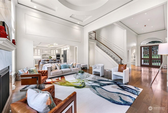 living room featuring french doors, dark hardwood / wood-style flooring, a towering ceiling, a fireplace, and ornamental molding