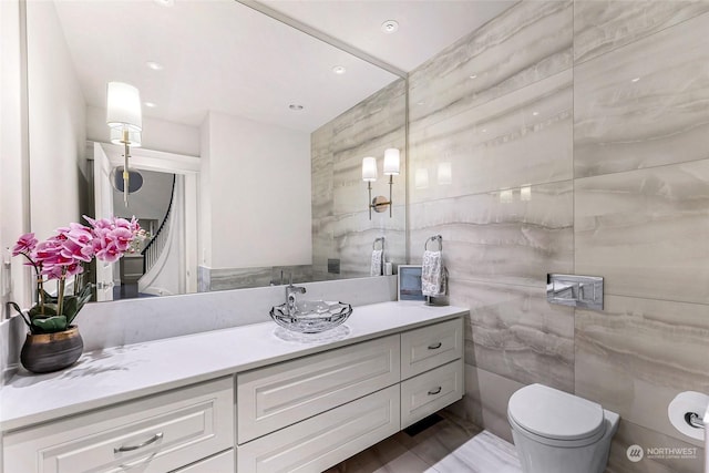 bathroom featuring vanity, toilet, and tile walls