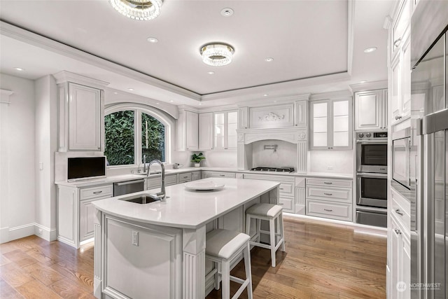 kitchen featuring white cabinetry, sink, a kitchen breakfast bar, an island with sink, and light hardwood / wood-style floors