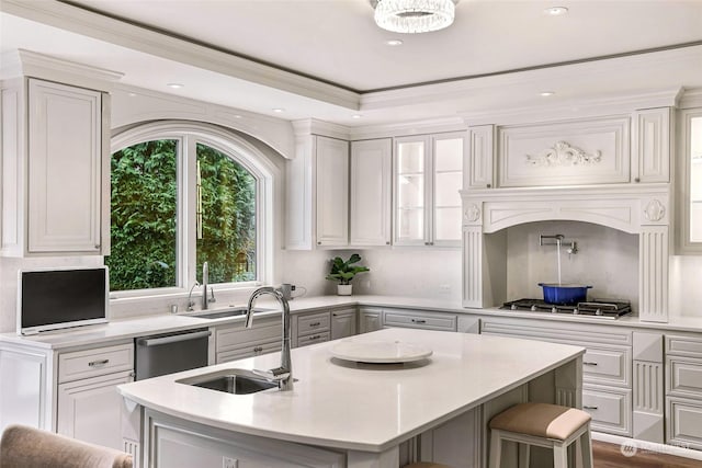 kitchen featuring a kitchen breakfast bar, stainless steel appliances, sink, white cabinetry, and an island with sink