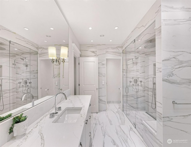 bathroom featuring a shower with door, vanity, and tile walls