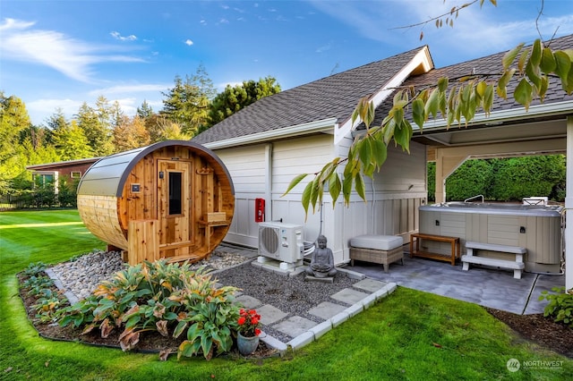 view of outdoor structure featuring a yard, a hot tub, and ac unit