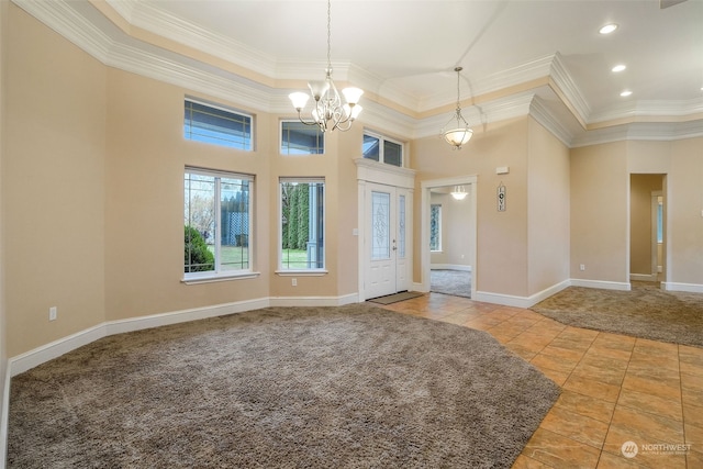 carpeted foyer featuring ornamental molding, a high ceiling, and an inviting chandelier