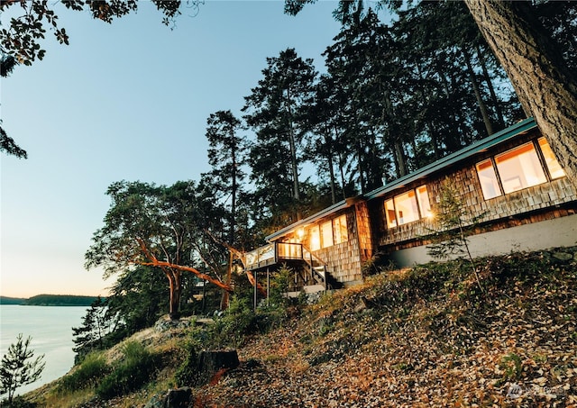 view of home's exterior with a deck with water view