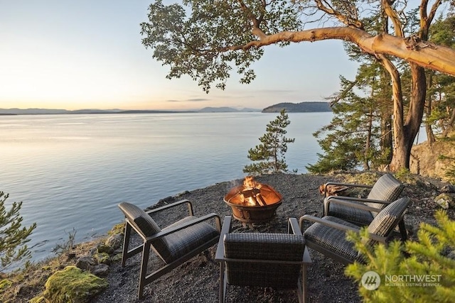 exterior space with a water view and an outdoor fire pit