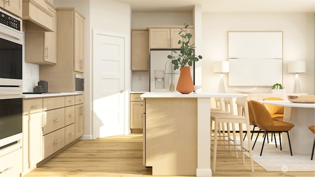 kitchen with light brown cabinets, light hardwood / wood-style flooring, white fridge with ice dispenser, tasteful backsplash, and a kitchen bar