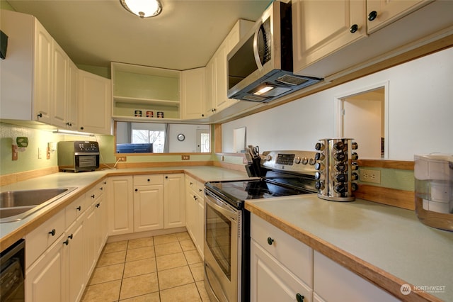 kitchen with white cabinets, light tile patterned floors, sink, and appliances with stainless steel finishes