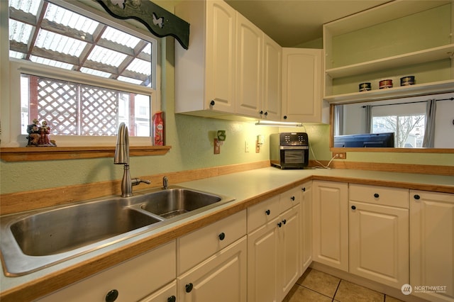 kitchen with white cabinets, light tile patterned flooring, and sink