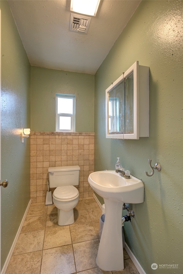 bathroom with tile patterned flooring, tile walls, and toilet