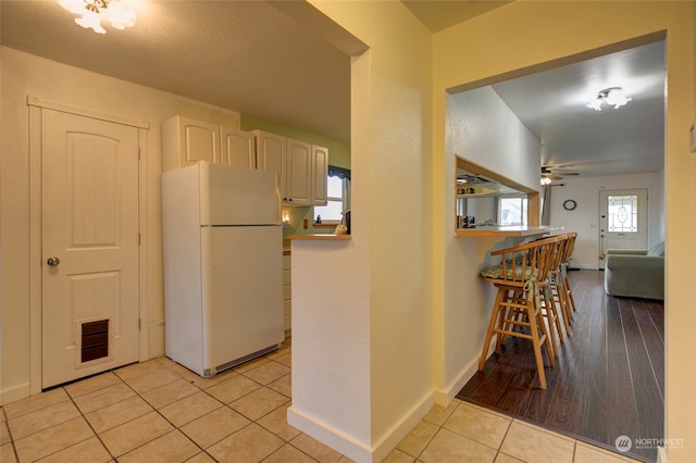 kitchen with light wood-type flooring, white fridge, and ceiling fan