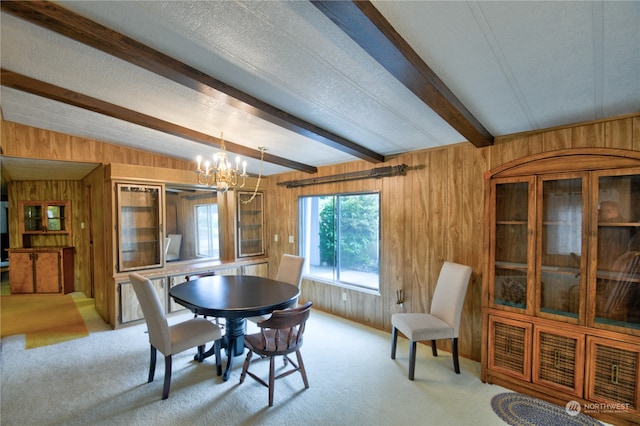 carpeted dining room featuring lofted ceiling with beams, wood walls, a textured ceiling, and a chandelier