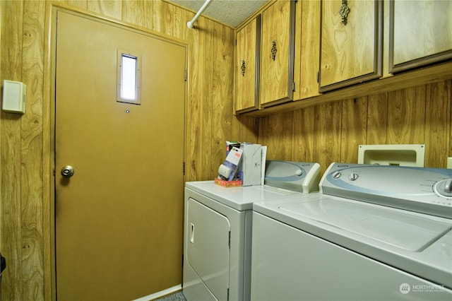 laundry area with cabinets, wooden walls, and washing machine and clothes dryer